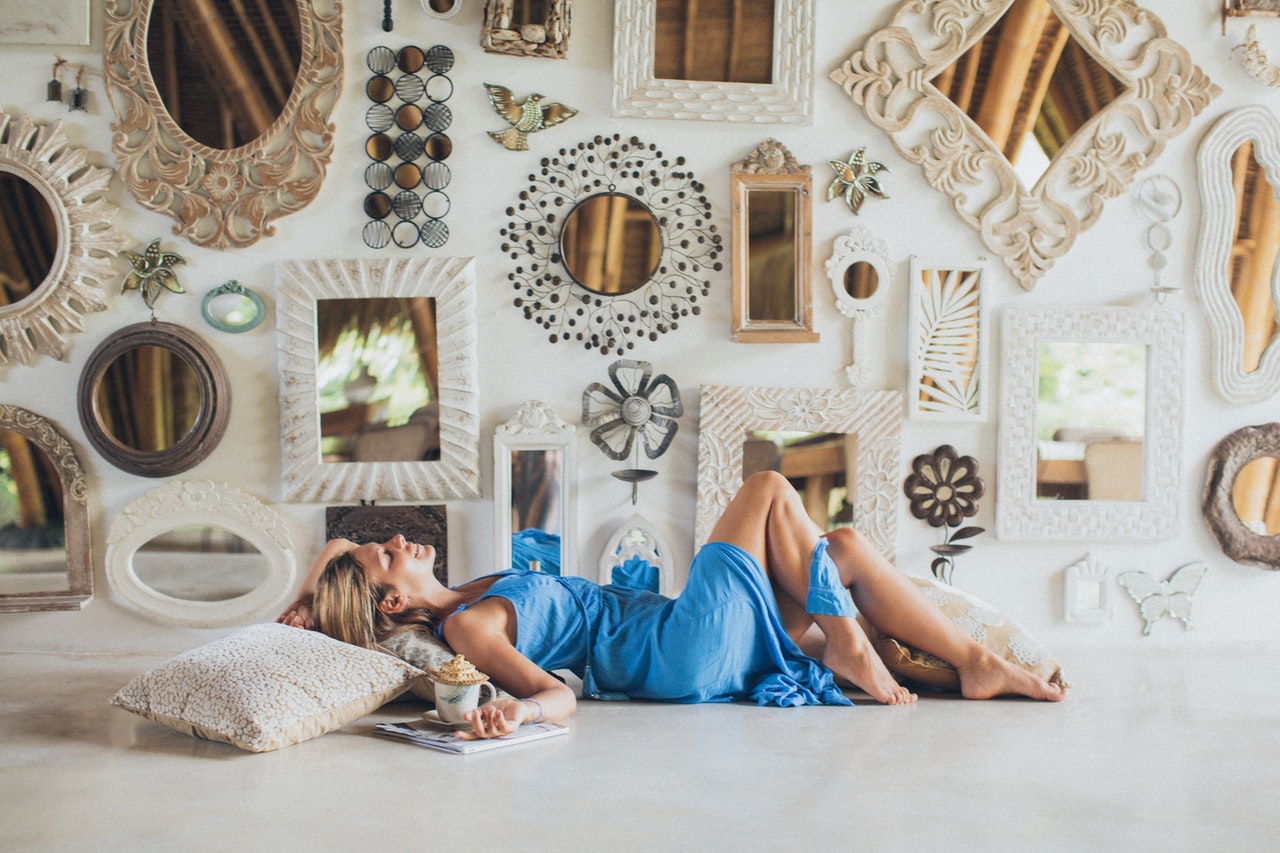 A woman lying on the floor near a wall full of mirrors.