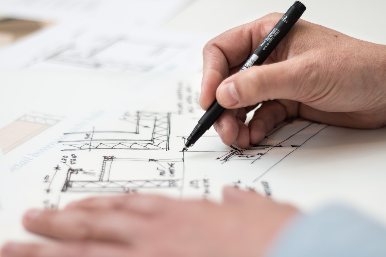 Person drawing house plans with a black pen.