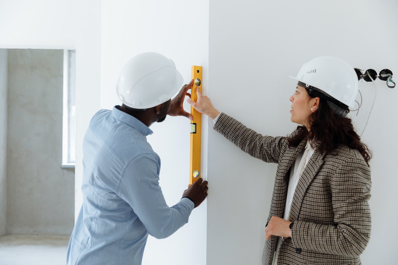 A man and a woman holding a level bar on the wall.