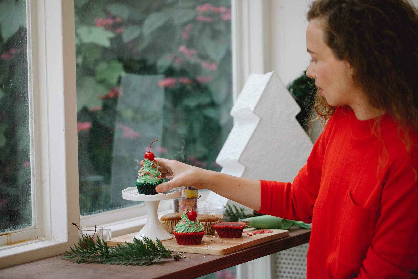 A woman placing cupcake decorations in the window