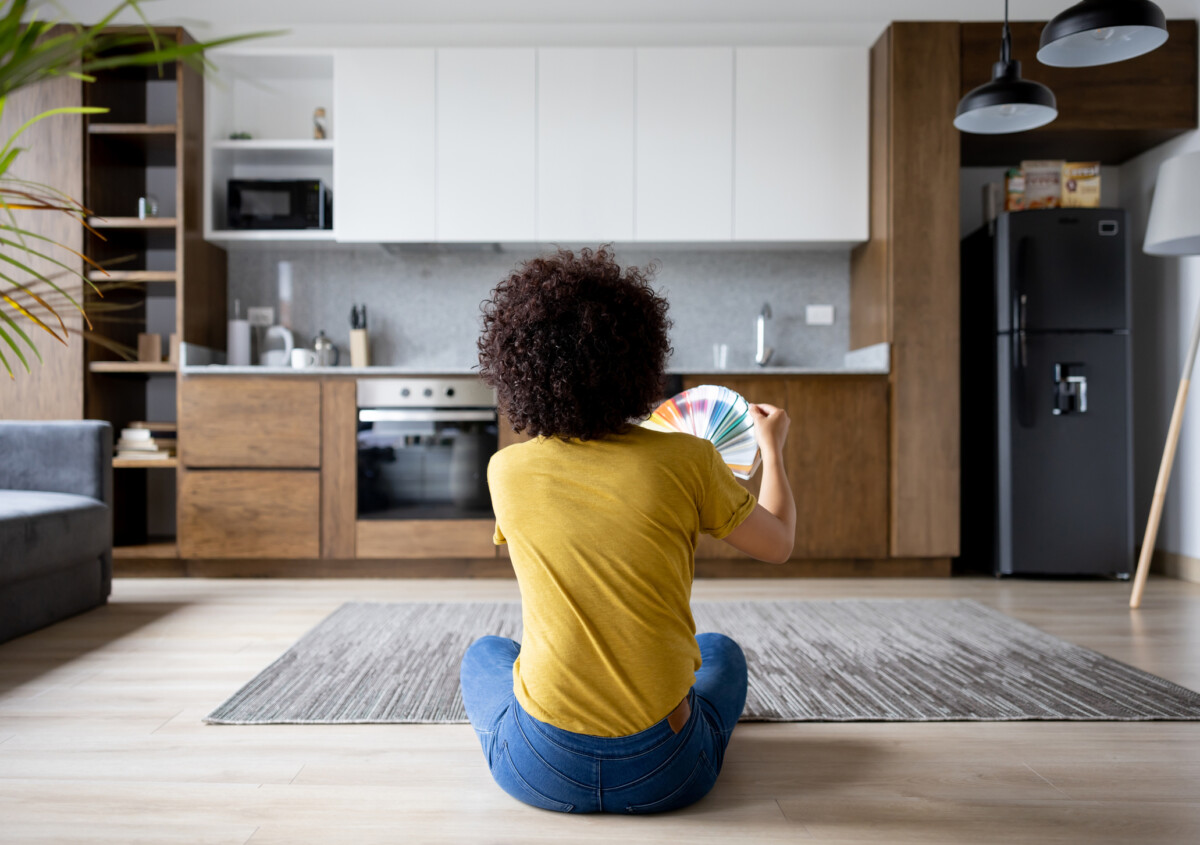 Casual woman at home choosing a color to paint the walls from a color swatch - home decor concepts