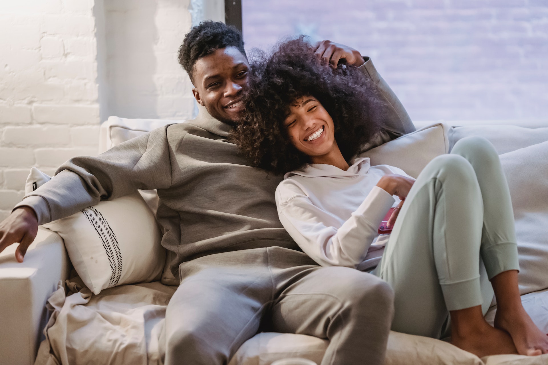 Happy couple laying on a couch and watching tv